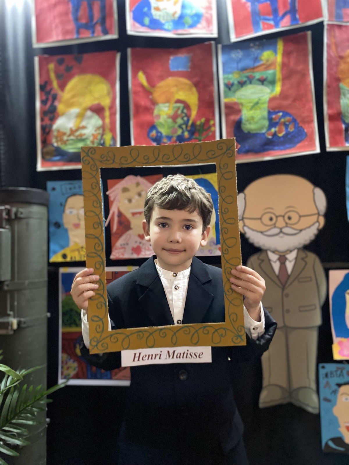 Хлопчик у костюмі Анрі Матісса з рамкою «Henri Matisse» на тлі дитячих малюнків