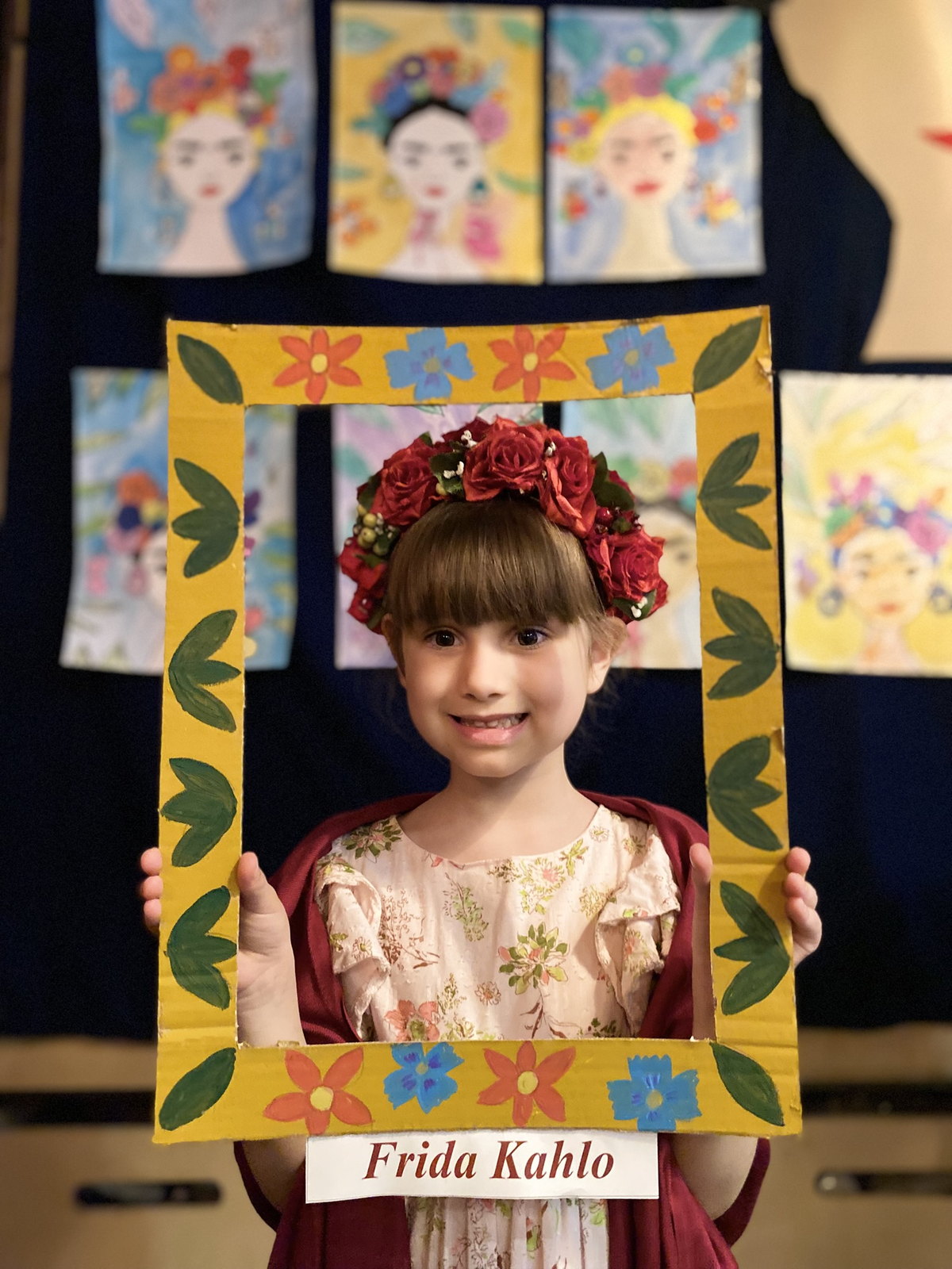 Дівчинка в образі Фріди Кало з вінком із червоних троянд і рамкою «Frida Kahlo»