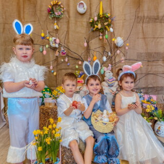 Четверо дітей у костюмах зайчиків із писанками на святкуванні Великодня в садочку